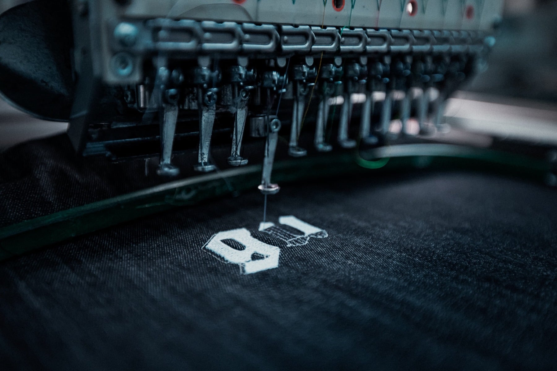 L'ago che ricama il logo Güller su denim nero